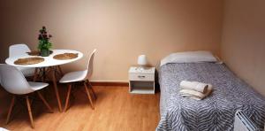 アルスーアにあるCastelao Apartmentsのベッド、テーブル、椅子が備わる小さな客室です。