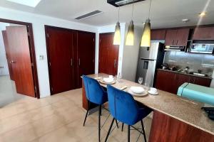 a kitchen with a table and blue chairs in a kitchen at Suite Jacuzzi Vista Río junto Hotel Wyndham 1 in Guayaquil