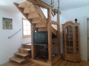 a room with a staircase with a tv and a shelf at Ferienhaus im Haus der Künste in Rhodt unter Rietburg