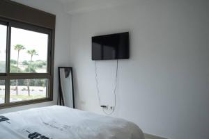 ein Schlafzimmer mit einem Bett und einem TV an der Wand in der Unterkunft Unique beach apartment in Rischon LeZion
