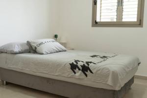 ein Bett mit einer weißen Bettdecke und einem Kissen in der Unterkunft Unique beach apartment in Rischon LeZion