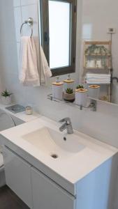 ein weißes Badezimmer mit einem Waschbecken und einem Spiegel in der Unterkunft Unique beach apartment in Rischon LeZion