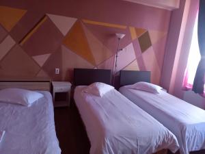 two beds in a room with a geometric wall at Pensiunea Vila Dana in Cluj-Napoca