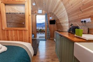 a bedroom with a bed and a kitchen with a sink at The Highland Bothies Glamping in Ullapool