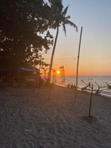 a sunset on a beach with trees and the ocean at KM Pension 