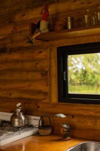 a kitchen with a stove and a window in a log cabin at Cabañas El Sosiego in Azul