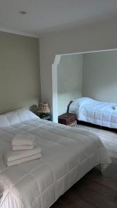 1 dormitorio con 1 cama blanca grande y espejo en 25puntocinco deptos Tandil en Tandil
