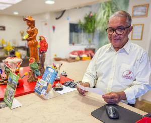 a man sitting at a counter holding a piece of paper at Jatobá Praia Hotel in Aracaju