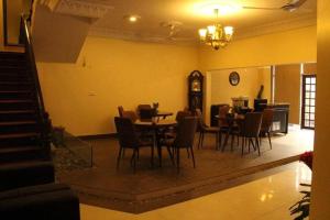a dining room with tables and chairs and a clock at Hotel Inn in Karachi