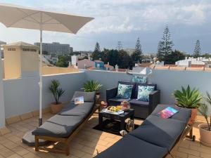 eine Terrasse mit Sofas und einem Sonnenschirm auf dem Dach in der Unterkunft Dunas de vilamoura in Quarteira