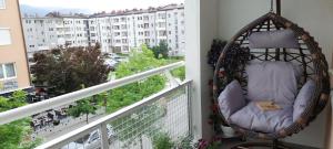 un fauteuil suspendu sur un balcon avec vue sur un bâtiment dans l'établissement Royal Place Apartment - East Sarajevo, à Lukavica