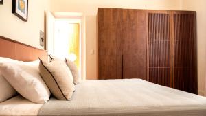1 dormitorio con 1 cama con almohadas y armario de madera en ConSentido Tamarindo en Mérida