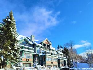 une grande maison avec de la neige sur le toit dans l'établissement Clairiere 406 /Spacious Mountain Home with SAUNA, à Mont-Tremblant