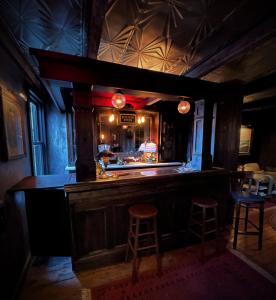 a bar in a pub with two stools and a counter at Crew's Quarters Boarding House - Caters to Men in Provincetown