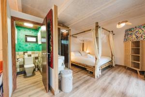 a bedroom with a canopy bed and a bathroom at Maxia Galega -Arte, Natureza, Relax -Ribeira Sacra in Monforte de Lemos