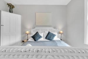 a white bedroom with a white bed with blue pillows at Poets Apartment with Free Parking By My Getaways in Worthing