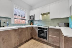 a kitchen with white cabinets and an oven at Poets Apartment with Free Parking By My Getaways in Worthing +9 photos