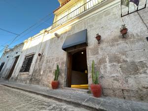 a building with two plants in front of a doorway at Hotel Piru Wasi in Arequipa