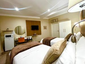 a hotel room with two beds and a desk at Swane’s guesthouse in Rustenburg