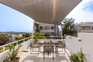 an outdoor patio with a table and chairs on a balcony at Vouliagmeni Stylish Homes by BluPine in Athens