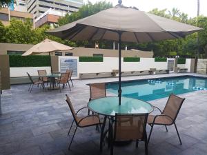 una mesa con sillas y una sombrilla junto a la piscina en Baja Inn Hoteles Rio, en Tijuana