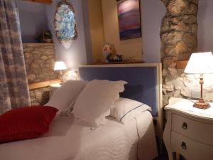 1 dormitorio con 1 cama con 2 lámparas y pared de piedra en Posada El Salin, en Muñorrodero
