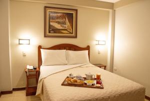 una camera d'albergo con un vassoio di cibo su un letto di Takana Inn a Tacna
