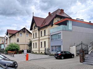 una casa grande con un coche aparcado delante de ella en Paderewskiego 9 Aparth en Leszno