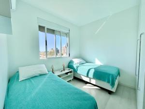 2 camas en una habitación blanca con ventana en Belo Apto com churrasqueira a 100m da Praia en Florianópolis