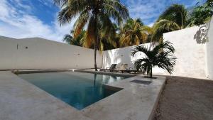 a swimming pool in front of a white building with a palm tree at Loft con alberca en Telchac in Telchac Puerto