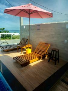 a pool with two lounge chairs and an umbrella at Pousada Viva Mar in Saquarema
