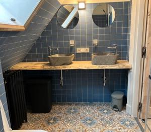 a bathroom with two sinks on a blue tiled wall at Schaapskooi 20 in Dwingeloo