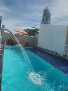 a swimming pool with a fountain in the water at Pousada Viva Mar in Saquarema