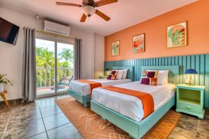 two beds in a room with a window at Bocas Paradise Hotel in Bocas del Toro