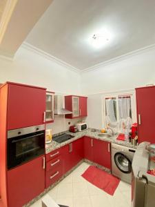 une cuisine avec des placards rouges et un lave-linge/sèche-linge dans l'établissement Appartamento a mohammadia AL KAWTAR, à Mohammedia