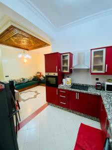 uma cozinha com armários vermelhos e piso em azulejo branco em Appartamento a mohammadia AL KAWTAR em Mohammedia