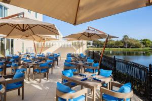 um restaurante com cadeiras azuis, mesas e guarda-sóis em The Karol Hotel, St. Petersburg Clearwater, a Tribute Portfolio Hotel em Clearwater