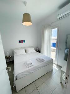 a white bedroom with a bed and a large window at Twins Apartments in Fanari