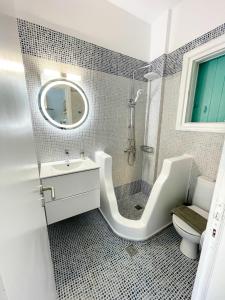 un bagno con lavandino, WC e specchio di Twins Apartments a Fanari