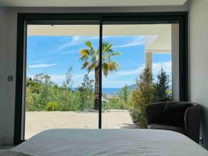 een slaapkamer met uitzicht op een palmboom door een raam bij Les Mimosas in Mandelieu-la-Napoule