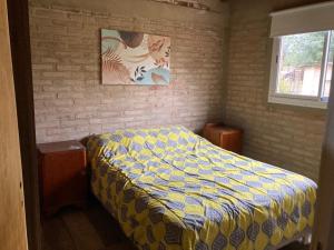 1 dormitorio con 1 cama con edredón amarillo y azul en cabaña Palmira en Santa Rosa de Calamuchita