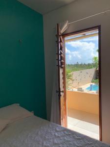 a bedroom with a bed and a view of a beach at Happy Hostel e Pousada Paracuru in Paracuru