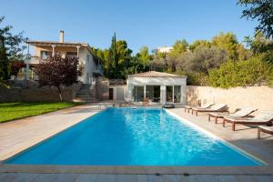 a swimming pool with chairs and a house at Stellar Villa Private Pool-Sea View in Porto Heli
