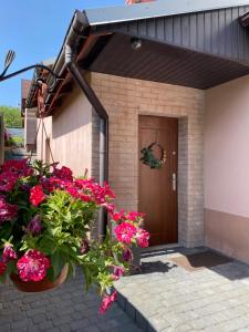 a house with pink flowers in front of a door at Agroturystyka ‚U Misia’ in Krzywopłoty