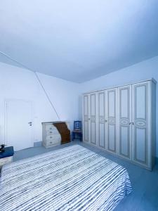 a white bedroom with a bed and a dresser at Bau!House in Piombino