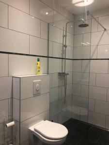 La salle de bains blanche est pourvue d'une douche et de toilettes. dans l'établissement Guest house à Chaudfontaine, à Chaudfontaine