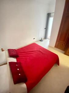 uma cama com um cobertor vermelho e almofadas em Appartamento a mohammadia AL KAWTAR em Mohammedia