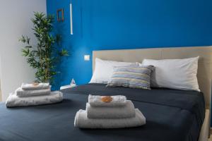 uma cama com toalhas com uma parede azul em Relaxroombeach em Anzio
