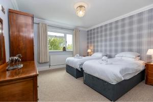 a bedroom with two beds and a desk and a window at The Lodge in Middlesbrough