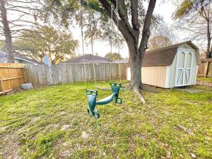 a green pipe sitting in a yard next to a tree at Comfortable Sleep 08 - Furnished Family Home with Spacious Backyard & Swing in Katy